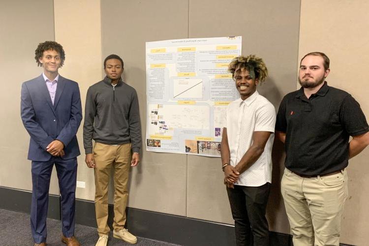 Four students at a poster presentation.